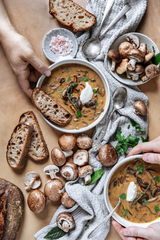 Two people with bowls of mushroom soups